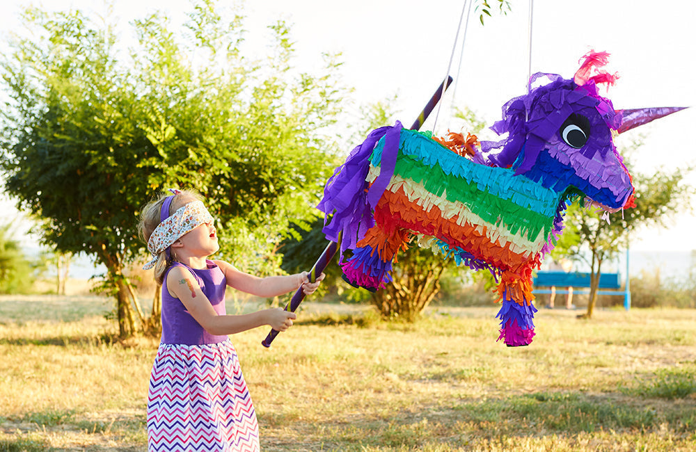 Mädchen schlägt eine Pinata mit einem Stock.